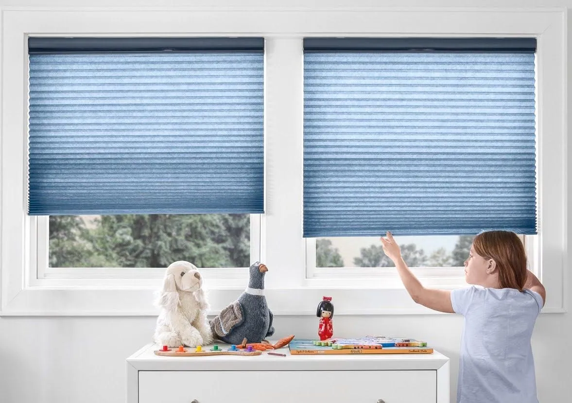 Young girl pulling her blue window shade down to keep out the summer heat, installed by Fasada Windows & Doors in Oakville.