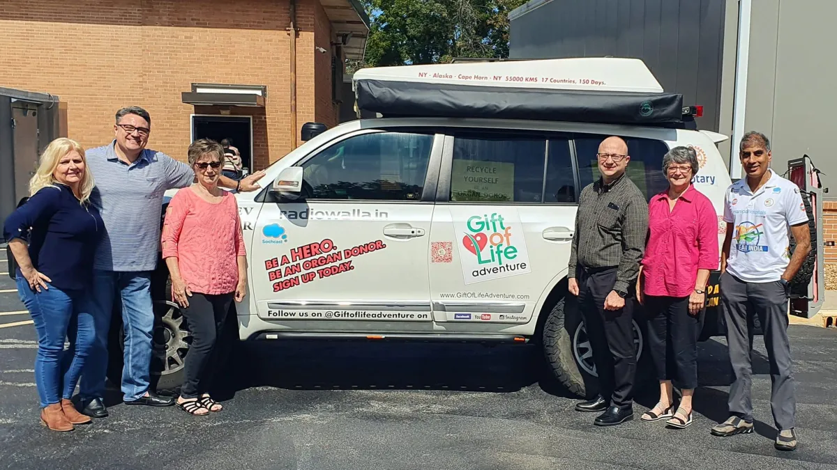 Rotary Club members and guest speaker Anil Srivatsa pose together in front of Anil's decorated car, promoting organ donation awareness during his 20,000-mile journey.