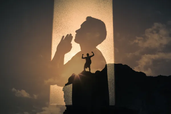 Man with praying hands praying to god for strength and courage.