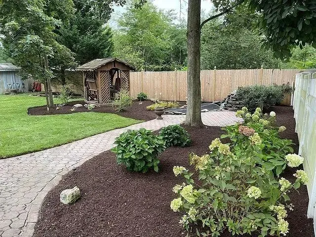 A serene backyard featuring a winding walkway surrounded by vibrant flowers and lush greenery in the garden.