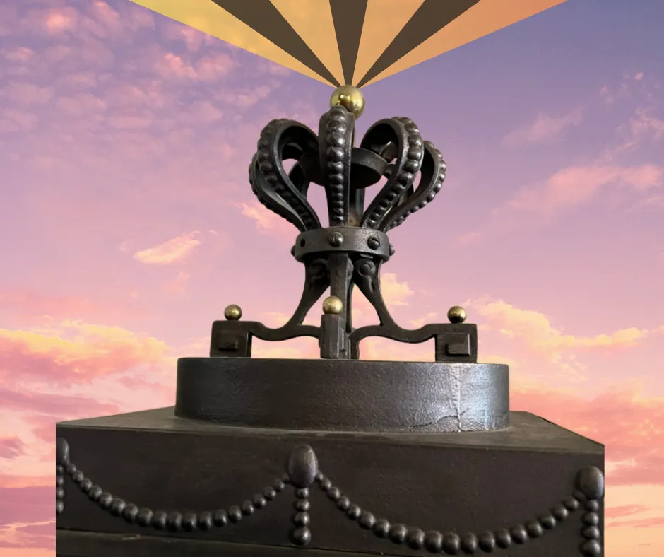 Crown with divine light above it and partly cloudy sky behind it.