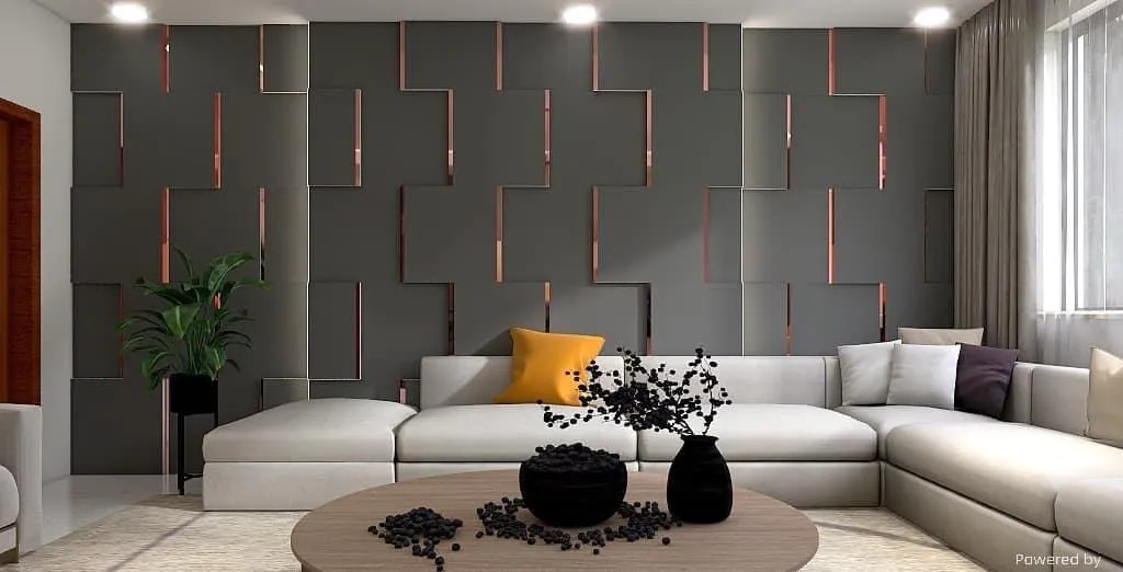 A modern living room featuring a large L-shaped beige sectional sofa adorned with neutral and mustard yellow cushions. The backdrop showcases a stylish geometric accent wall with vertical cut-out patterns and warm lighting peeking through. A round wooden coffee table with black decorative vases and berries sits in front of the sofa. Natural light filters in through a window with sheer curtains, and a tall green indoor plant adds a touch of freshness to the sleek, contemporary space.