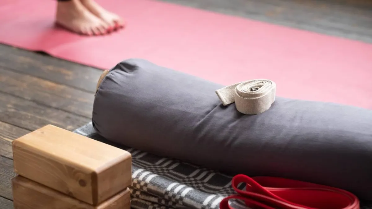 Woman on yoga mat next to yoga equipment