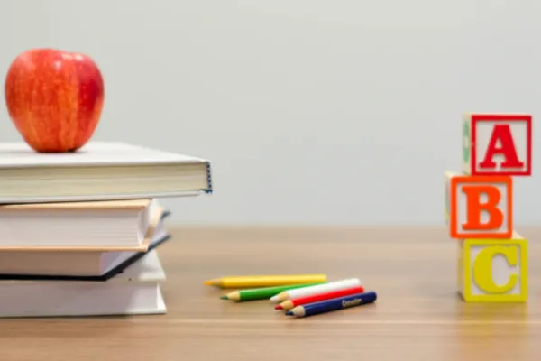 Books, pencils, and alphabet blocks on a desk symbolising study and foundational learning for yoga teacher training.