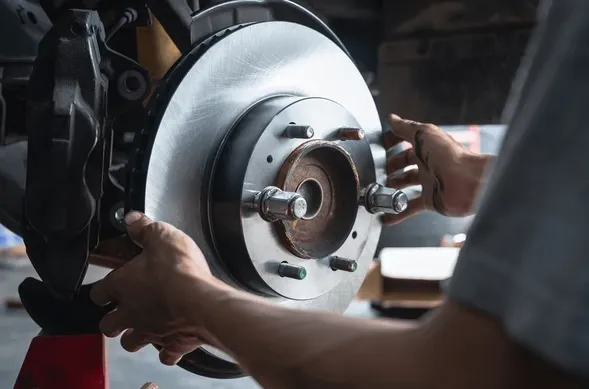 Brake repair in progress as a mechanic installs a new rotor at Paradise Automotive Service in San Juan Capistrano.