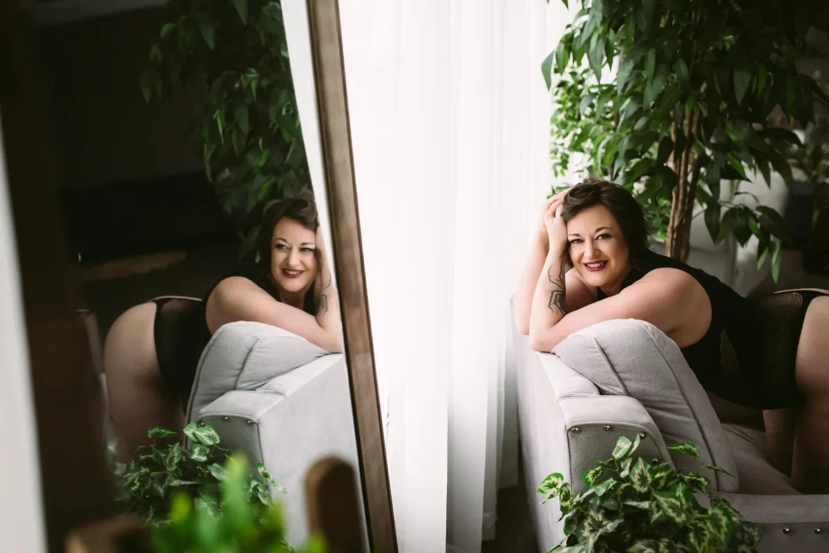 A woman with dark hair lounges over a grey couch