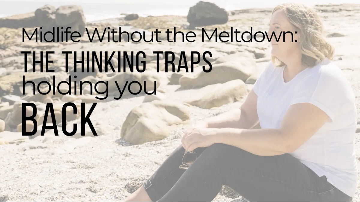 Tamsin Acheson sitting on a rocky beach in a white t-shirt, looking out to sea, with blog title text overlay: “Midlife Without the Meltdown: The Thinking Traps Holding You Back.”
