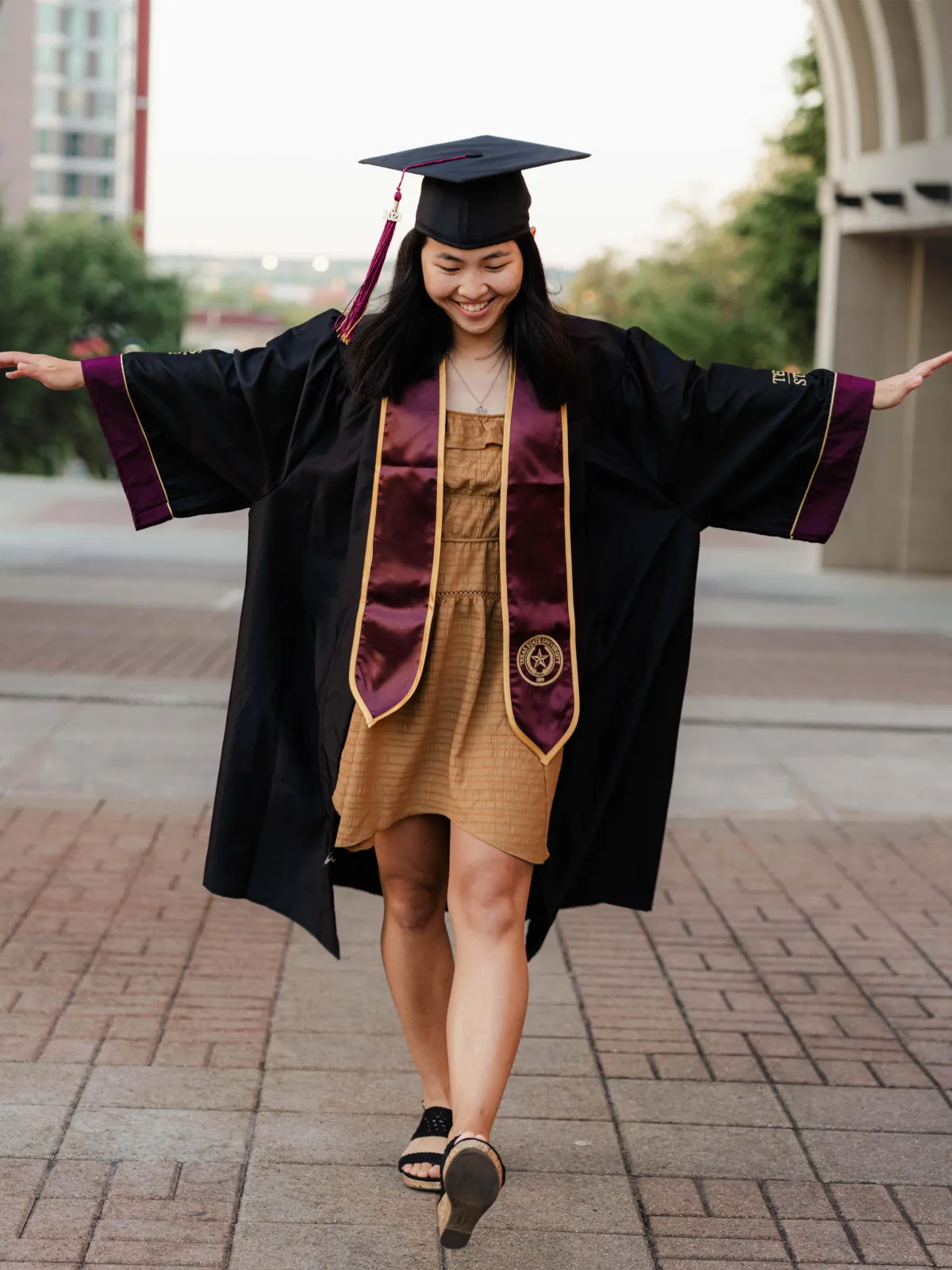 Texas State University graduate reflecting on their journey during a photoshoot.