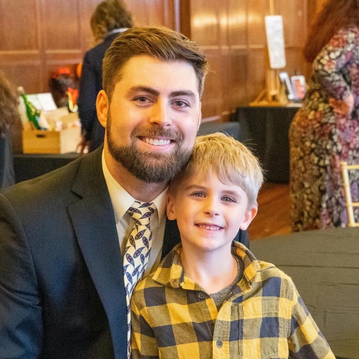 Matt Apple, Founder and CEO of Walking For Rochester, smiling while seated indoors with his young son, both looking at the camera and sharing a warm moment.