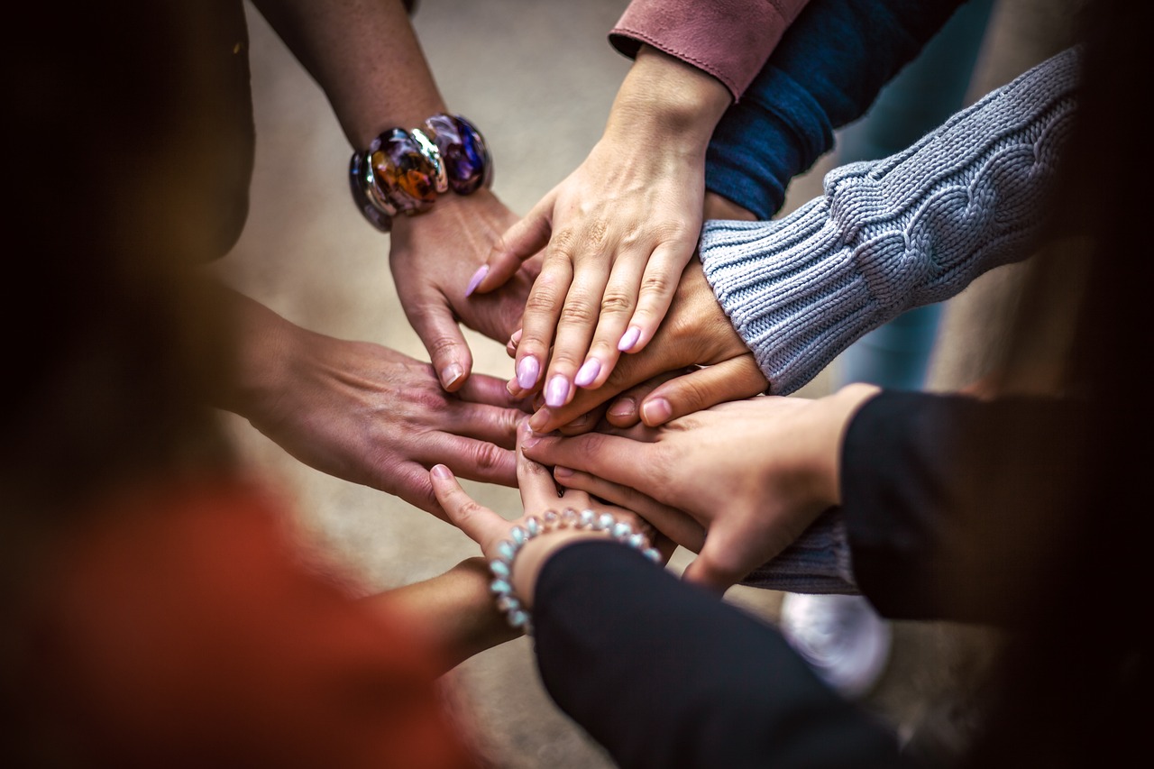 an image of hands placed in the centre of a circle to show community
