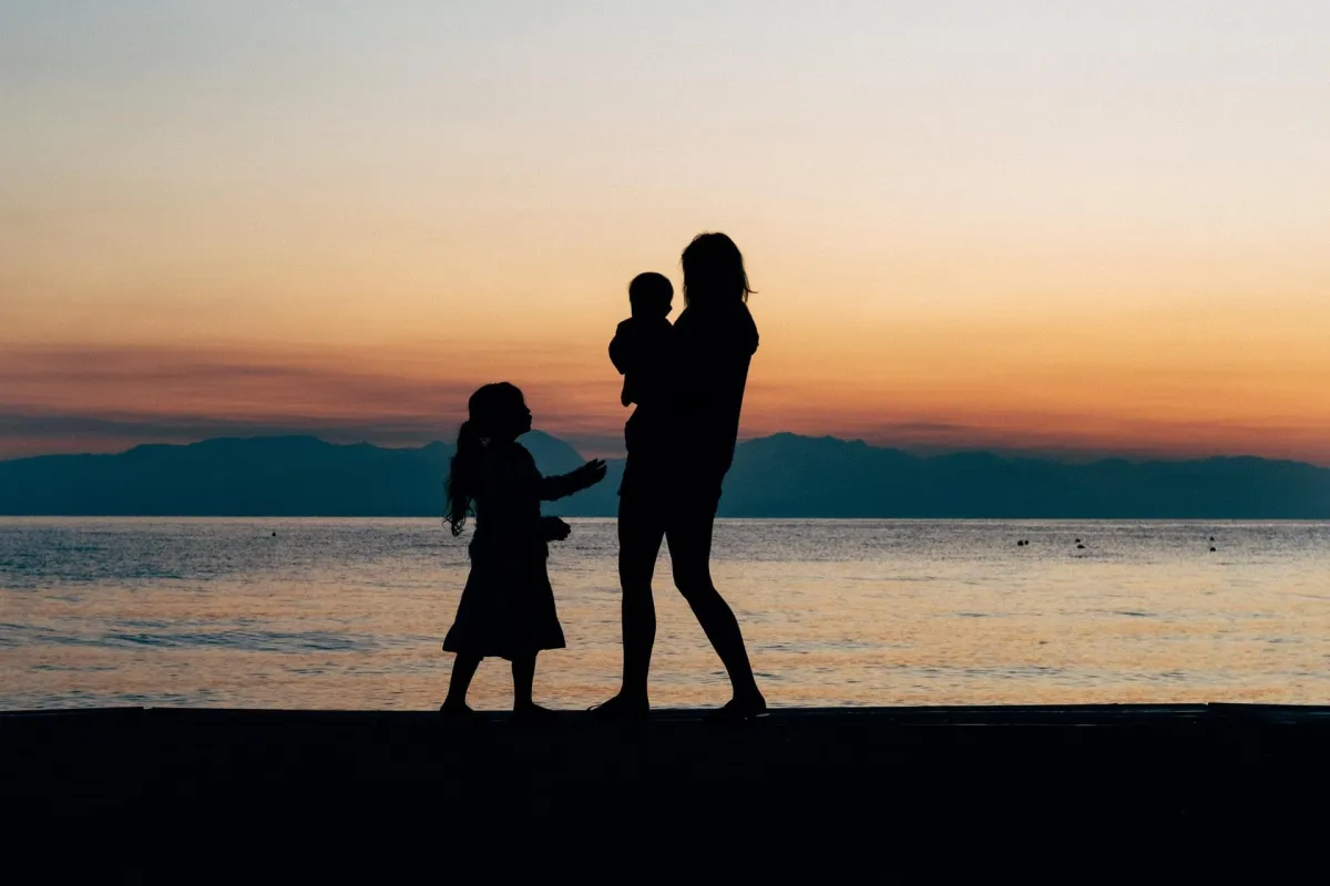 mother holding children at sunset