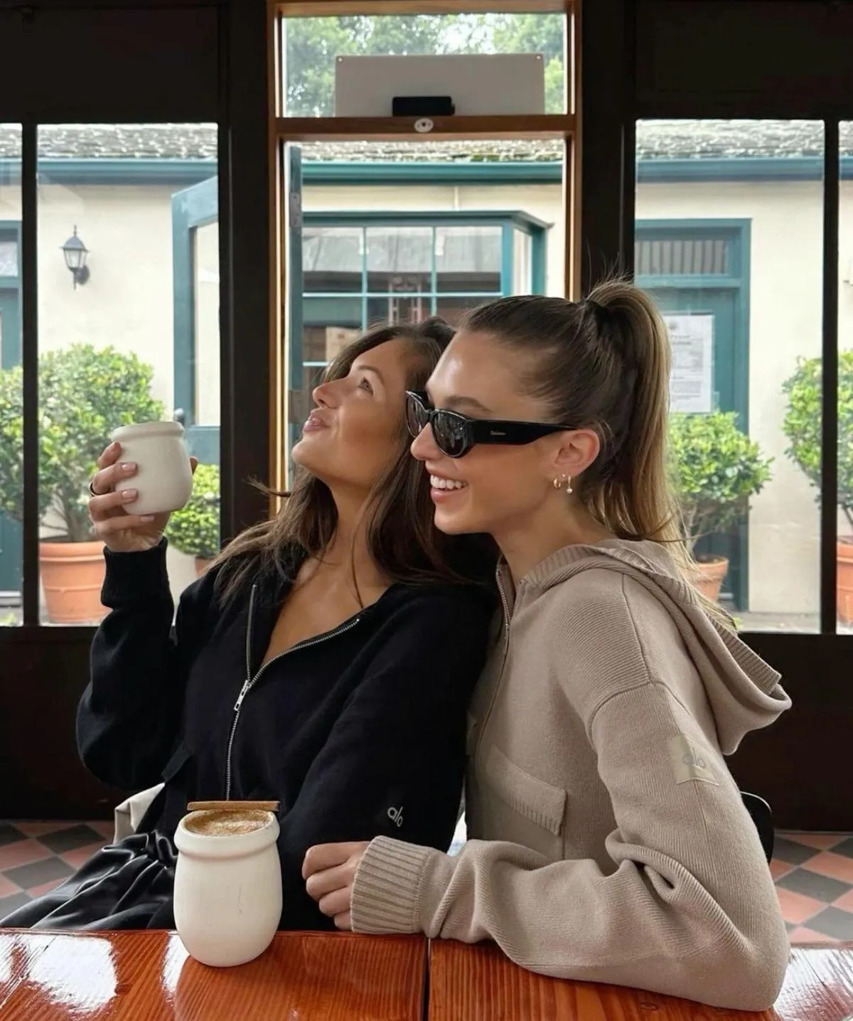 two girls sitting in a cafe laughing together