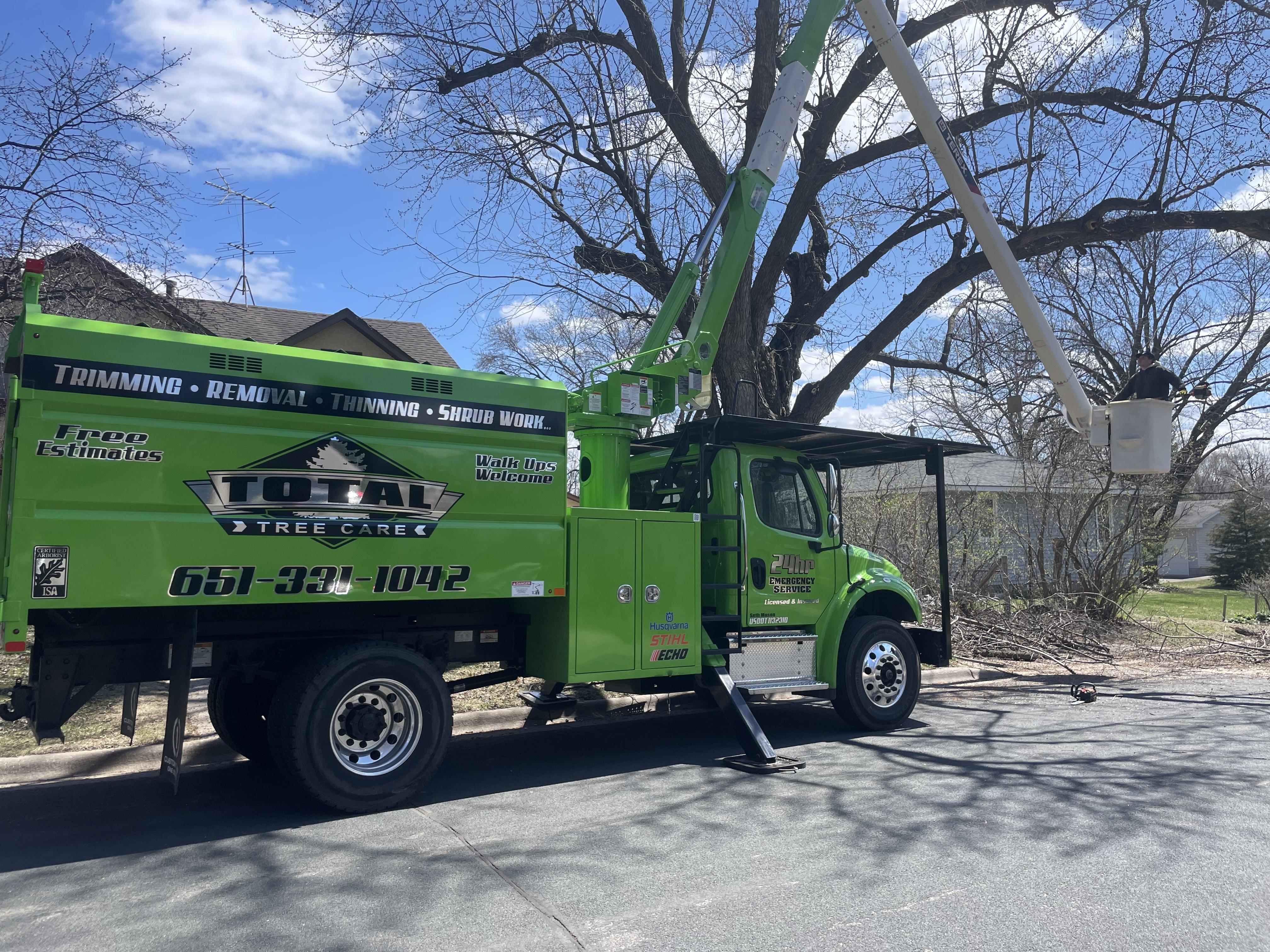 "Total Tree Care truck and crane performing tree trimming"