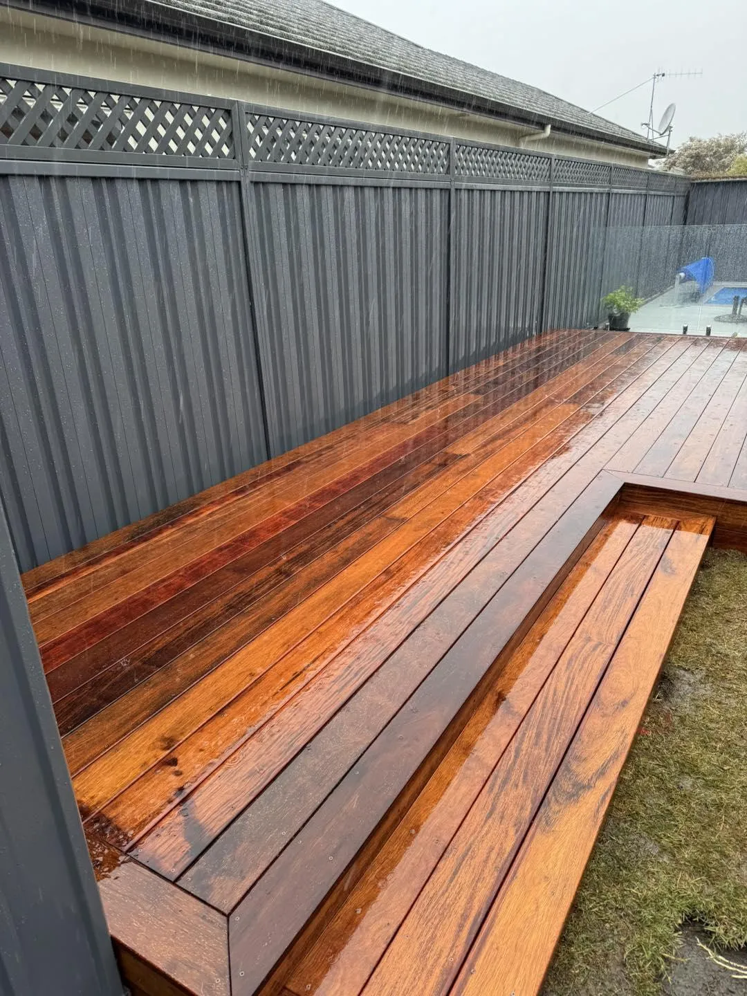 Glossy timber bench seat installed against grey fence, showcasing custom carpentry and outdoor seating builds in Hawke's Bay by Mitch's Maintenance