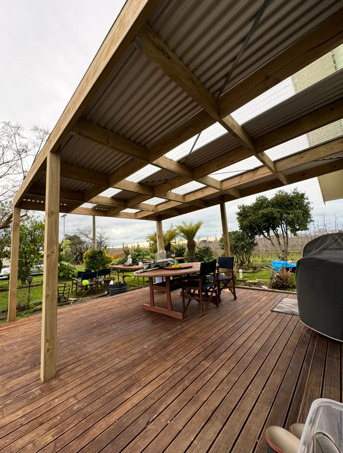 Outdoor timber deck under corrugated roof with dining furniture, representing pergola and deck construction for outdoor living spaces in Hastings, Hawke's Bay by Mitch's Maintenance