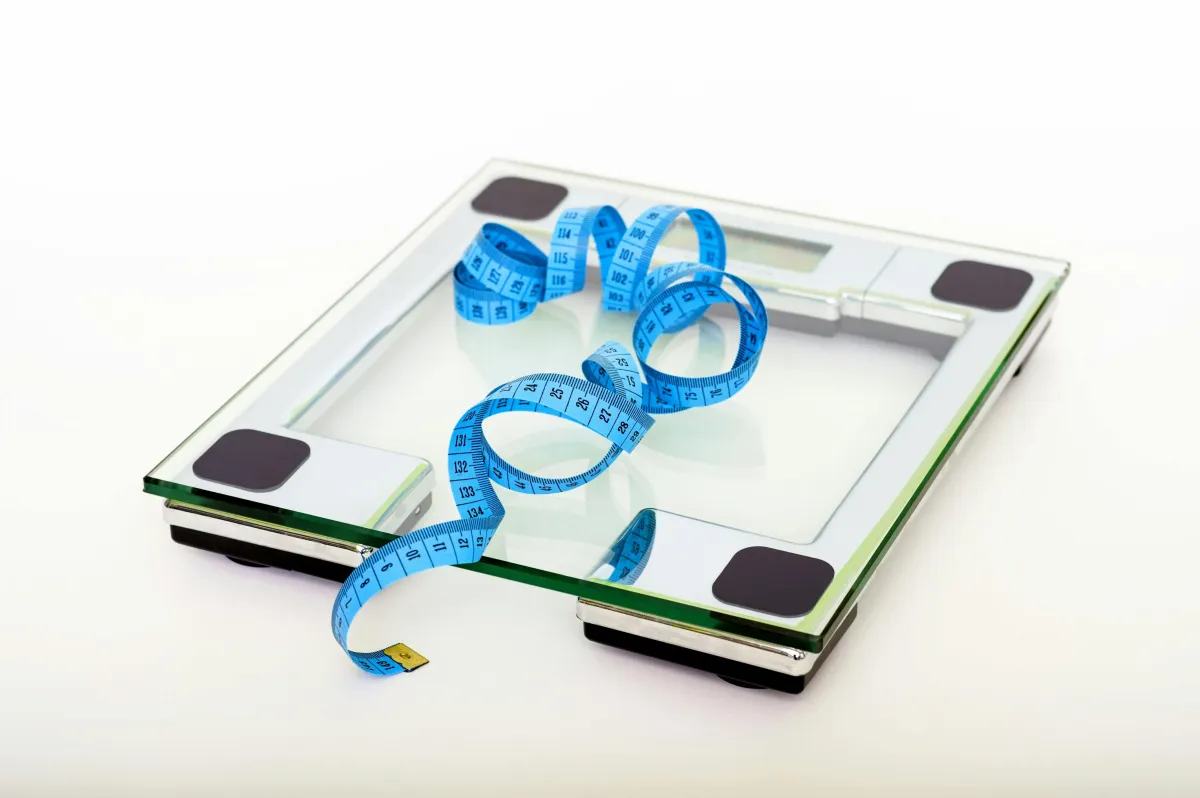 glass scale with blue tape measure on top with white background