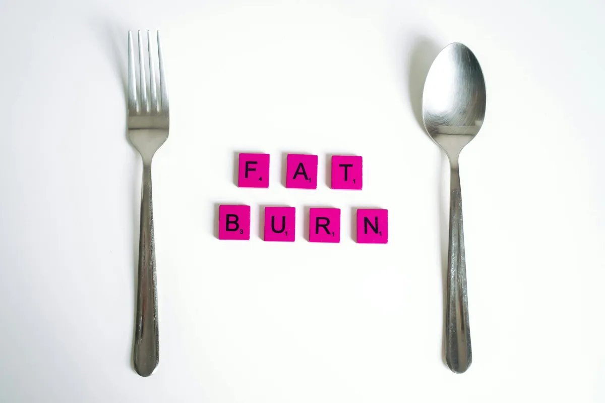 fat loss in pink letters with for and spoon on white surface
