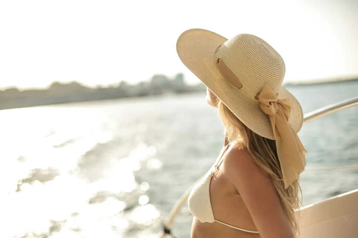 woman in hat by water in sun