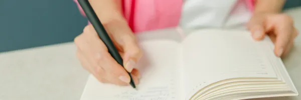 Close up of a woman's hands writing in a journal.