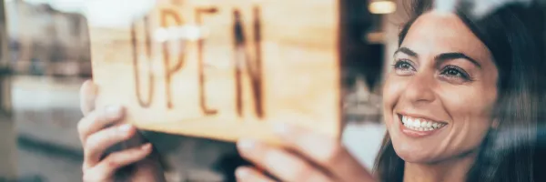 Woman holding an 'Open' sign for a new business