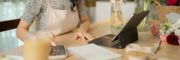 Woman working at desk with a laptop and iPhone calculator