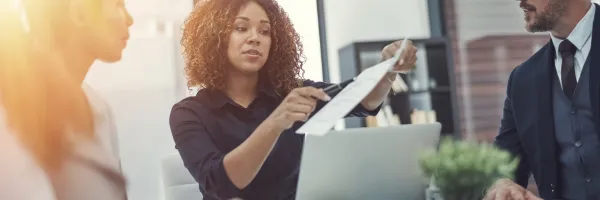 Three young, entrepreneurial business people around a desk completing a business review