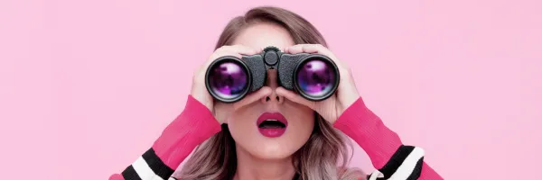 Woman looking through binoculars with a surprised look on her face
