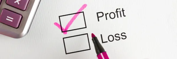 Paper with two boxes for profit and loss - the profit box is ticked with a pink pen