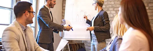 Group of casually dressed business people looking at results on a flip chart.