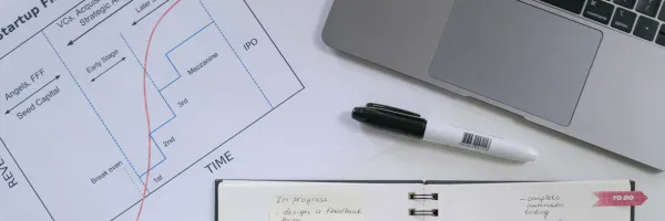 Laptop, paperwork with a graph on and a diary on a desk.