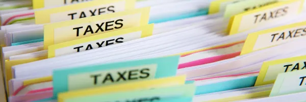Paper filing with tabs reading TAXES in bright colours