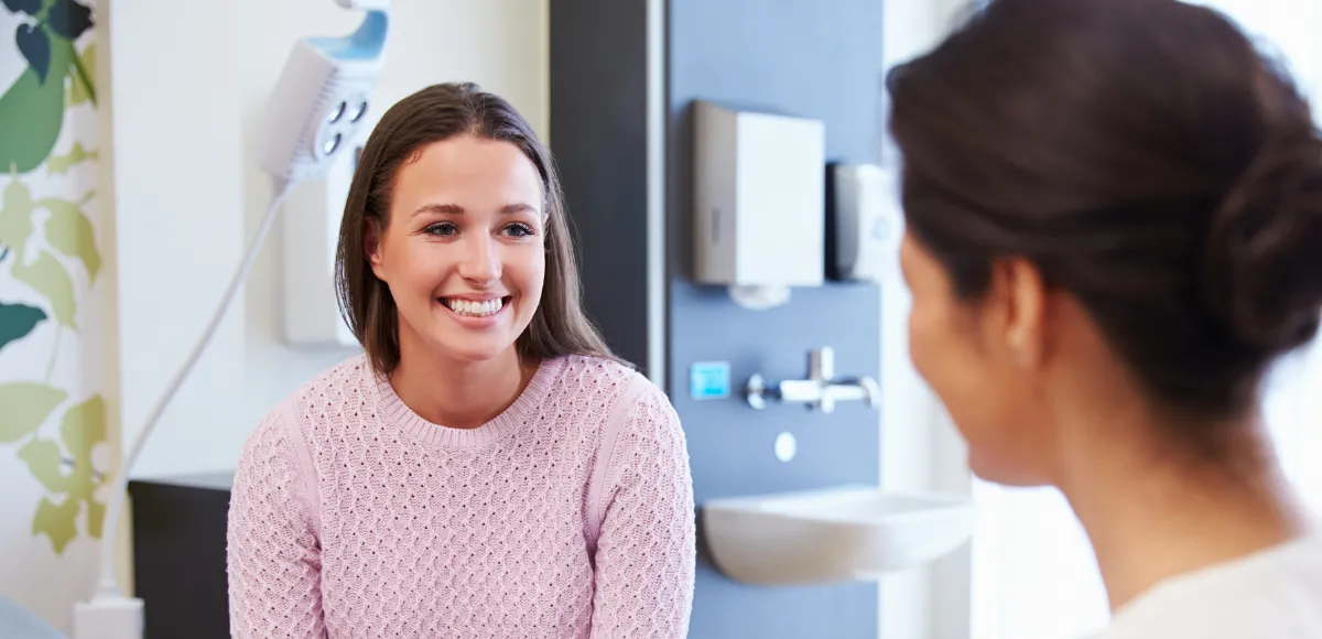 women patient sitting and smiling at a woman doctor