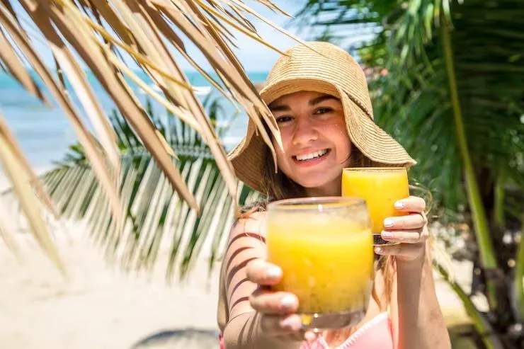 Girl holding a glass of juice in a beach