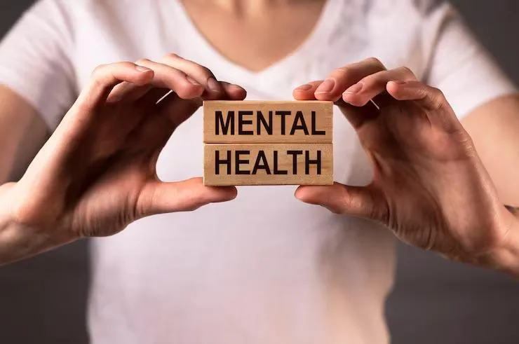 A black woman holding a block that reads "Mental health""