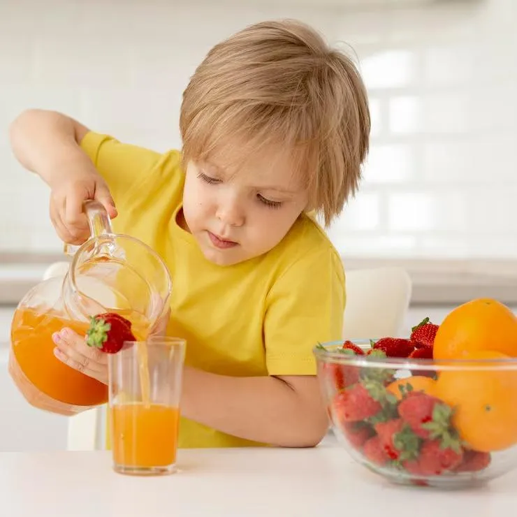 A kid pouring juice in a glass