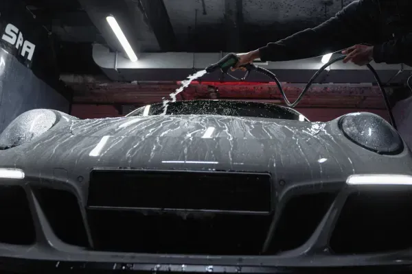 Car getting washed with high-pressure rinse in a detailing bay