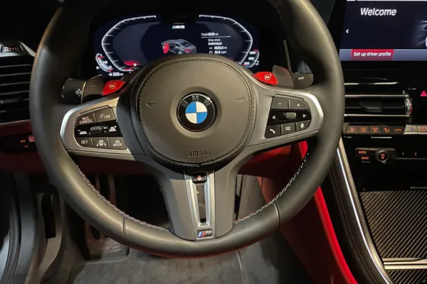 BMW M sport steering wheel with digital dashboard and red interior accents