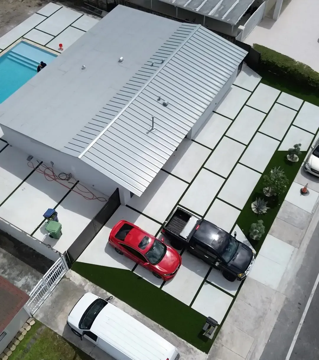Modern concrete driveway with artificial turf inlay strips by Concrete Designs LLC in Miami-Dade FL