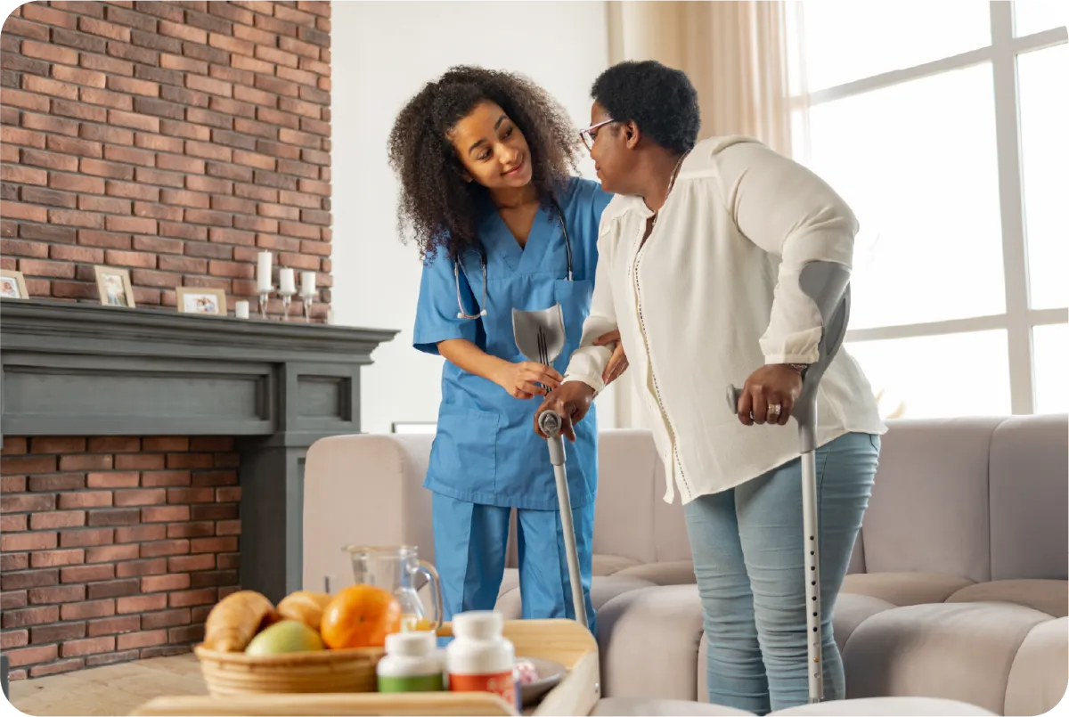 A female caregiver assisting a senior female to walk
