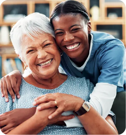 A black nurse hugging a white elderly woman