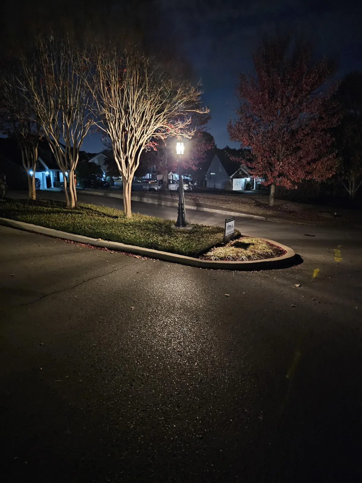 In an overwhelming darkness, a classic street lamp shines brightly, illuminating the entrance with a soft warm glow. 