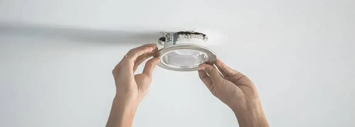 A person's hands install a ceiling light