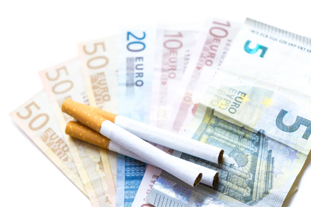 Imagen representando el coste del tabaquismo con cigarrillos sobre billetes, destacando el ahorro económico al optar por la hipnosis para dejar de fumar.