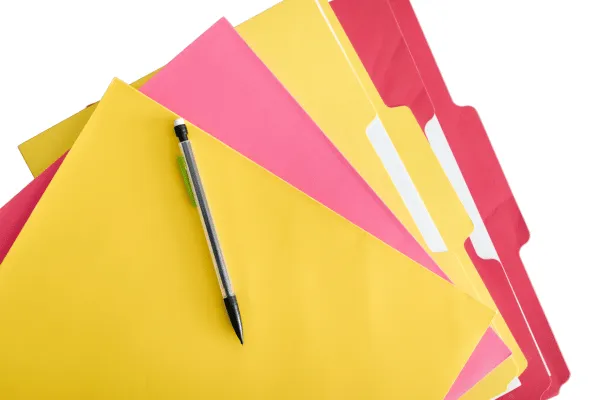 A black pen resting on brightly coloured file folders, symbolising secure record-keeping and data protection as outlined in the privacy policy for Jane Stratton Biology Tutor.