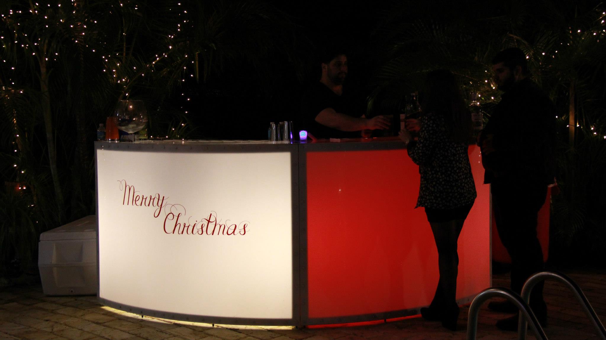 Lighted bar with a “Merry Christmas” sign at an outdoor event.