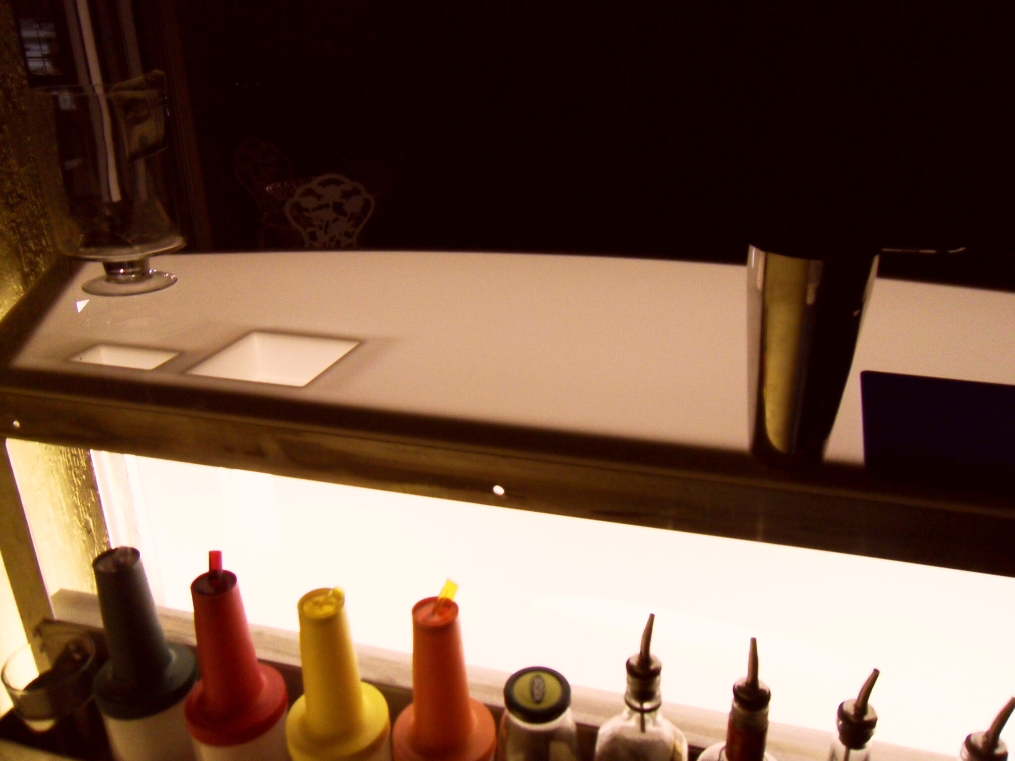 Bar counter with drink tools and bottles.