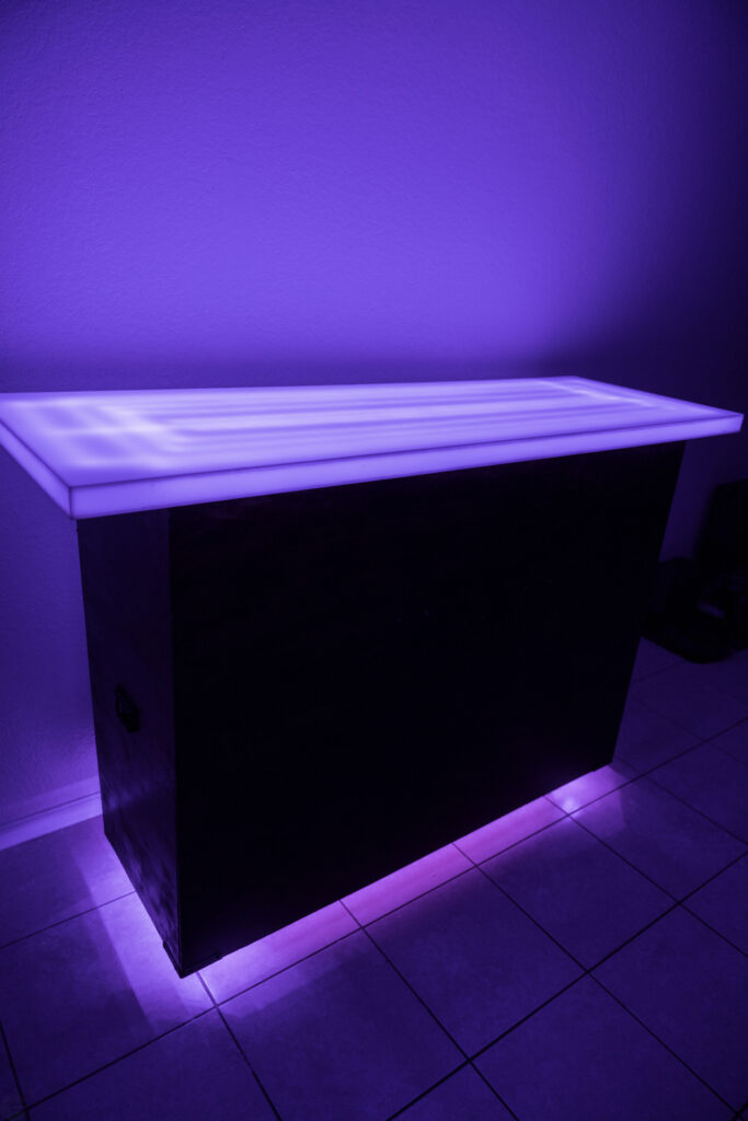 Illuminated bar counter with purple lighting.