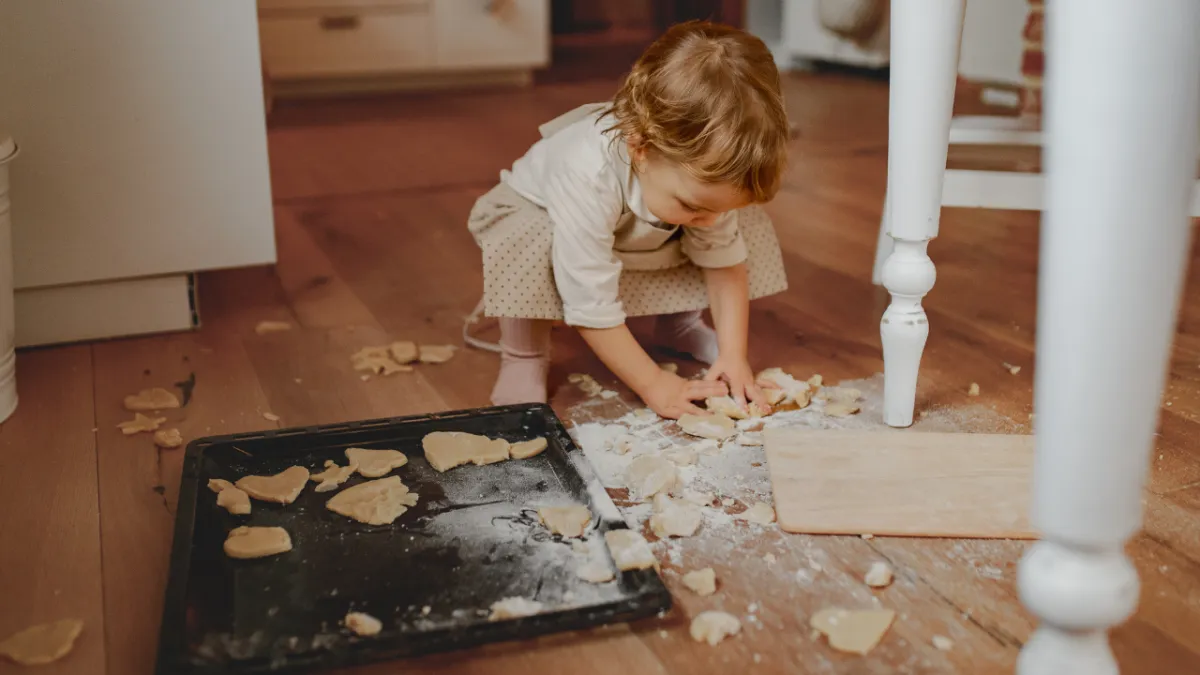 Toddler baking sugar cookies on the kitchen floor with flour spilled everywhere, representing how a messy house can reflect joyful family memories instead of mom guilt.