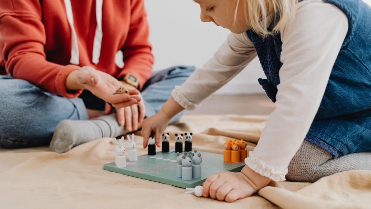 Mom stepping back while child builds confidence and problem-solving skills during board game