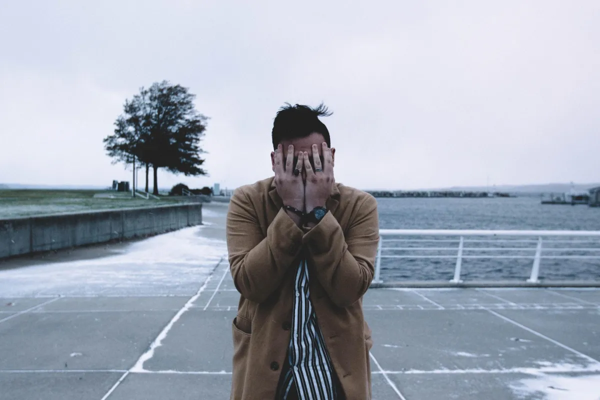 man with hands covering face